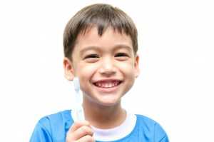 Little boy smiling while holding a tooth brush