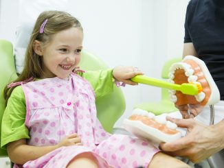 Dentist Teaching a Young Girl How To Properly Brush Her Teeth
