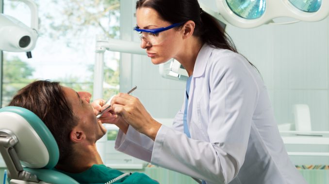 Man being checked by dentists Man being checked by dentists