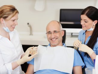 Man being checked by two dentists