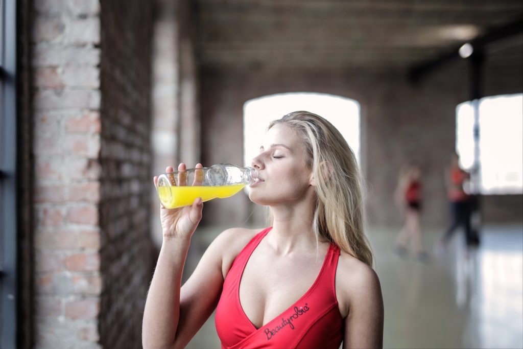 woman drinking juice after work out