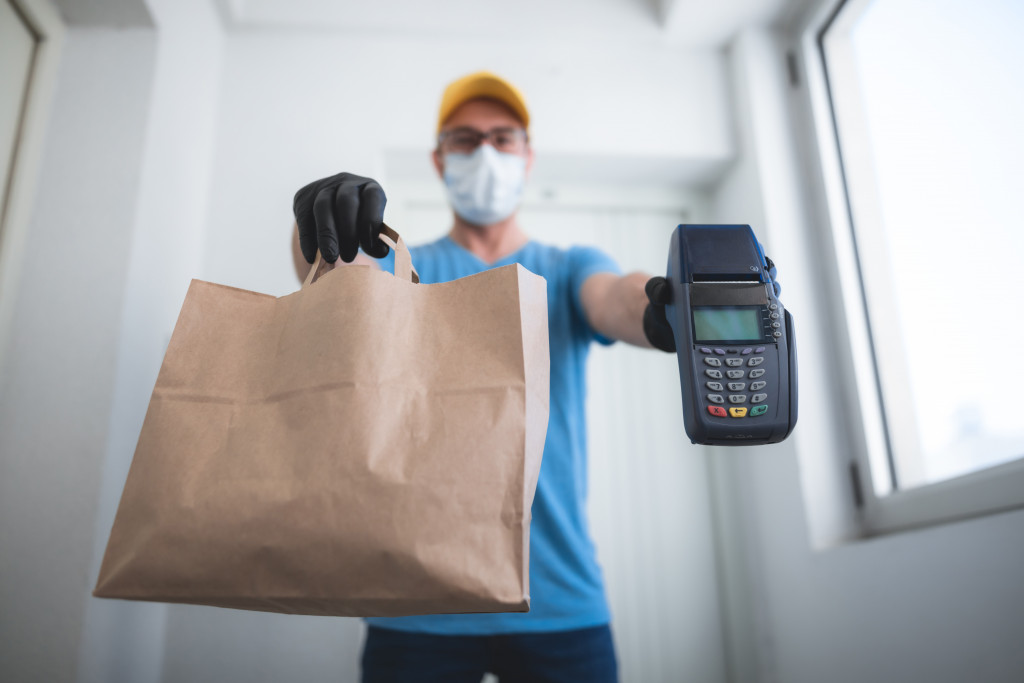 Delivery man with a shopping bag and a POS device