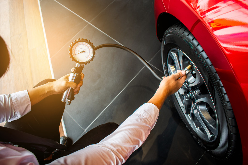 Car owner checking the air pressure of the tire of his vehicle.