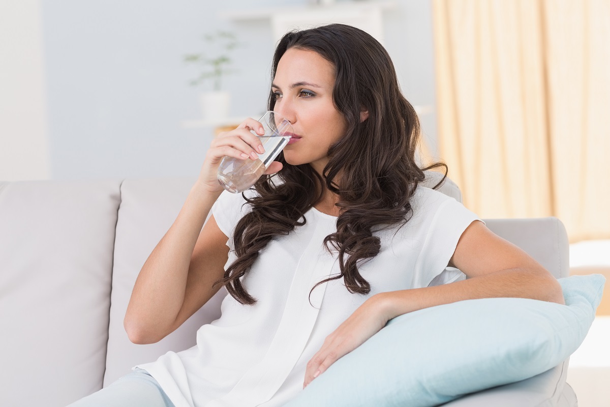 woman drinking water on couch